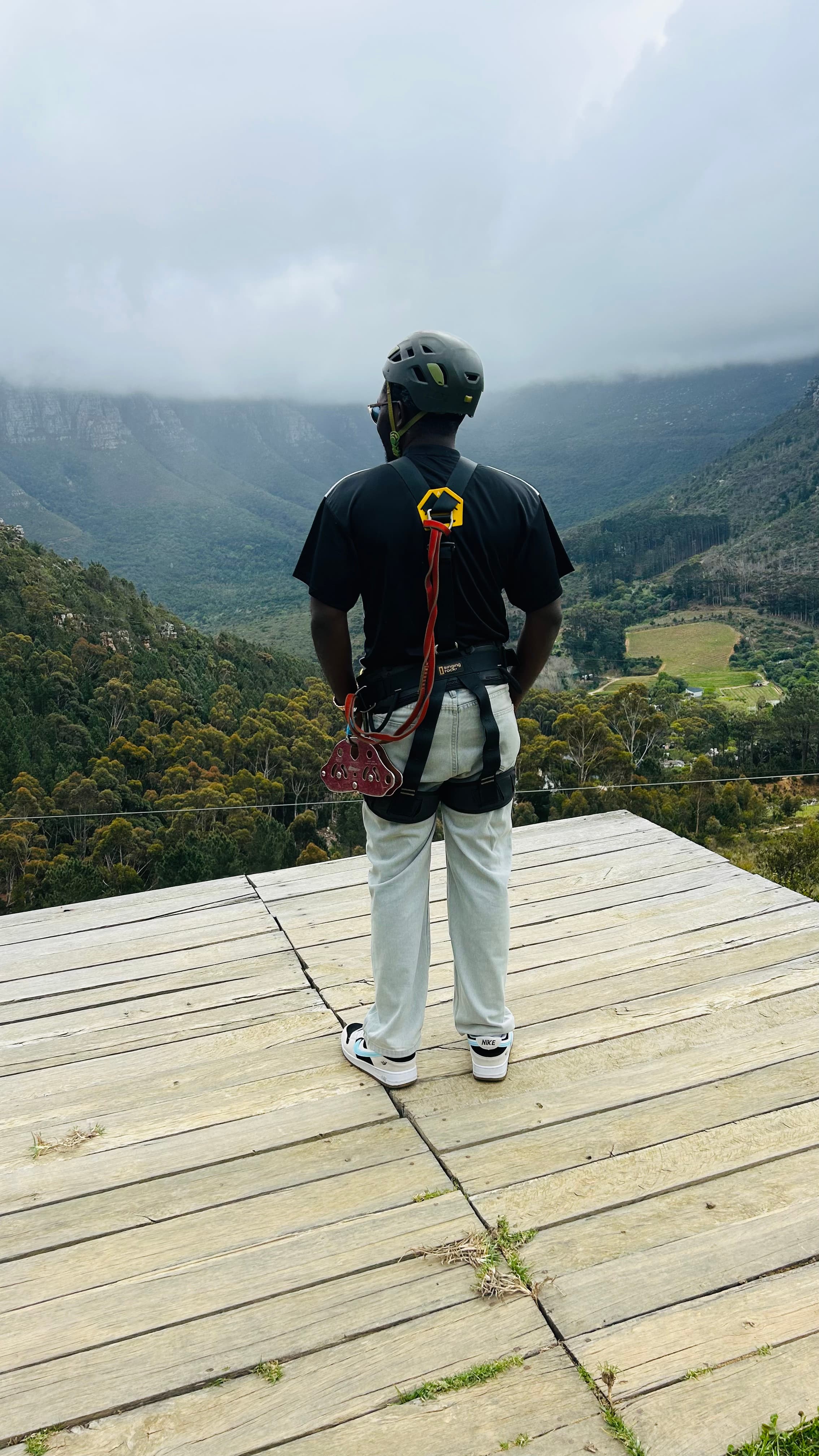 Standing in a zip-line harness overlooking the mountains, Cape Town